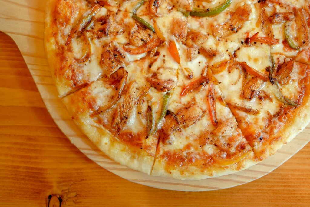 Delicious close-up view of a hot chicken pizza topped with onions and peppers.
